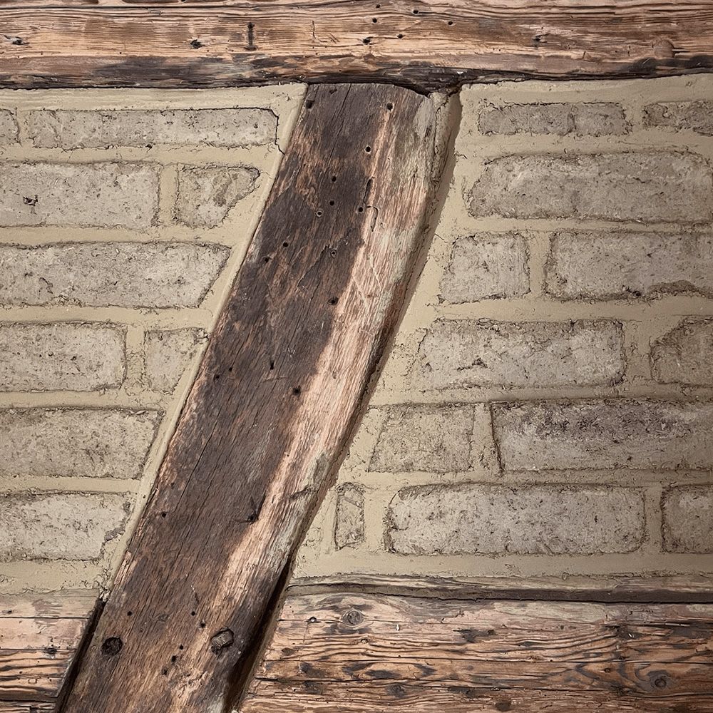 Nahaufnahme eines Fachwerkhauses mit sichtbaren verwitterten Holzbalken und Lehmfüllung